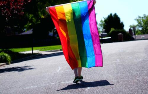 person-walking-while-holding-rainbow-colored-flag-2433122-scaled